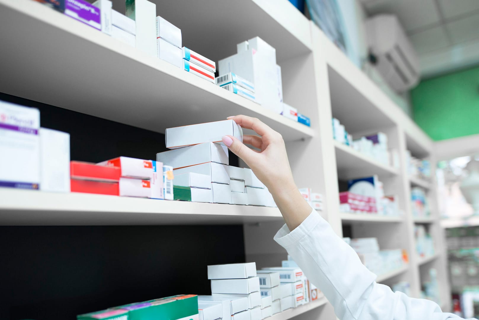 closeup view pharmacist hand taking medicine box from shelf drug store scaled